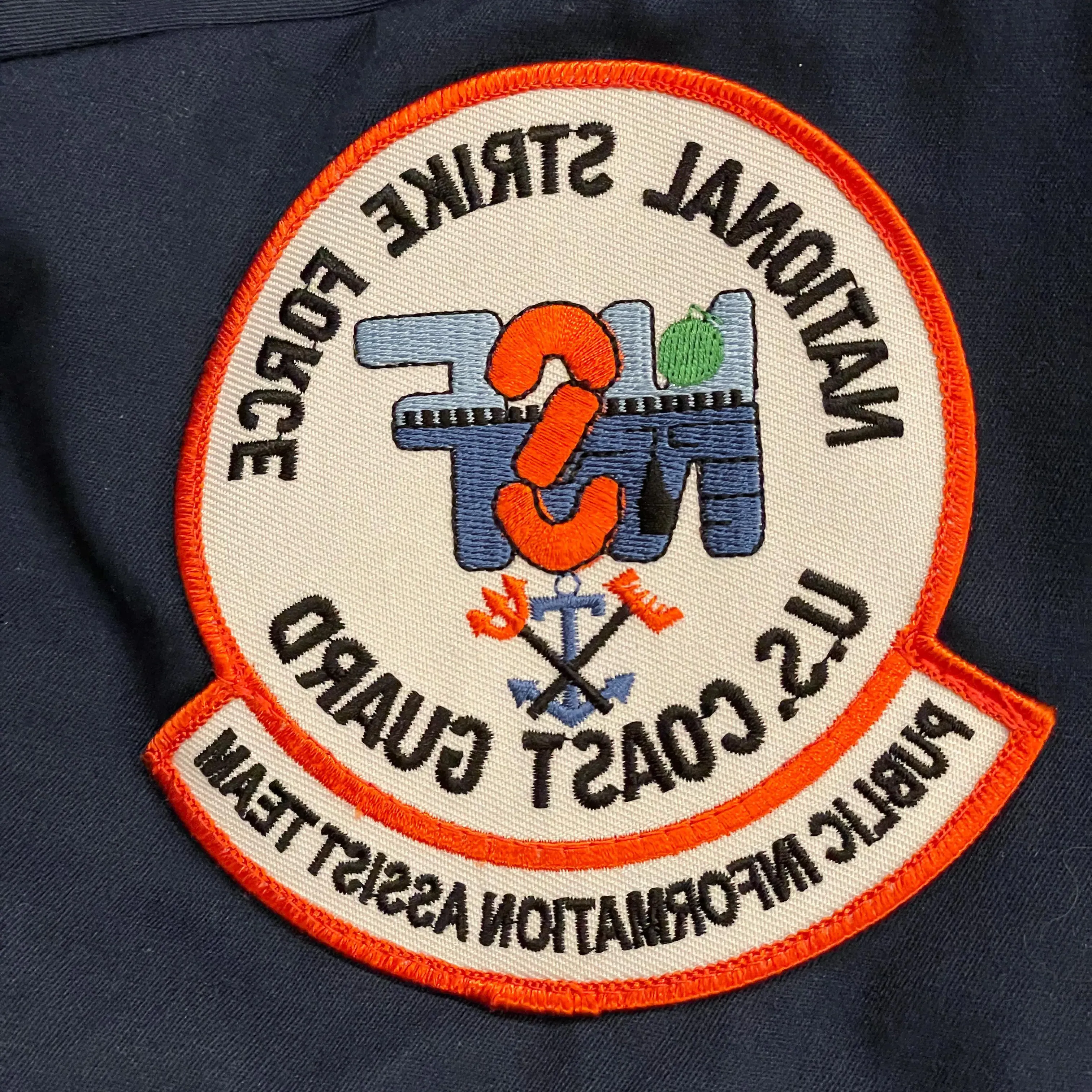 制服上的徽章，上面写着“美国国家打击部队”.S. Coast Guard. Public Information Assist Team"